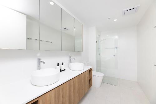 a white bathroom with two sinks and a shower at Solaris 606 in Forster