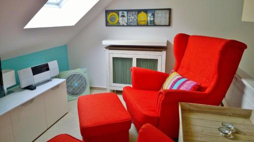 a living room with a red chair and a tv at Ostsee Ferienappartement Dierhagen-Strand in Dierhagen