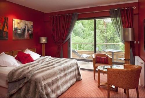 a bedroom with a bed and a table and a window at Logis La Source Bleue in Gudmont