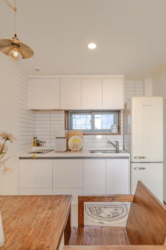 a kitchen with white cabinets and a white refrigerator at Le Village Aewol F in Jeju