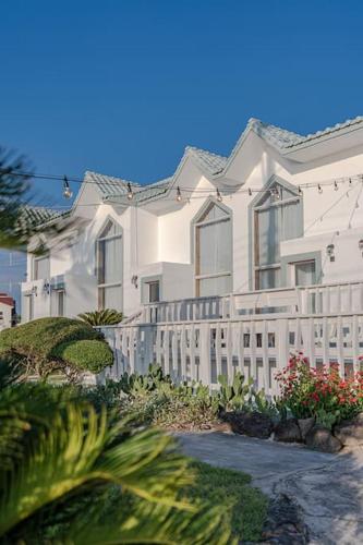 a large white house with a white fence at Le Village Aewol F in Jeju