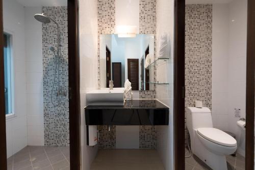 a bathroom with a sink and a toilet and a mirror at 1Br Poolside Apartment, Long Beach, Lanta Sport Resort 109 in Ko Lanta