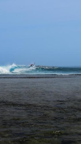 a surfer riding the waves on a beach at Sumatra Surf Resort in Biha