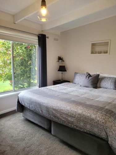 a bedroom with a large bed and a large window at Healesville Schofield Cottage in Healesville