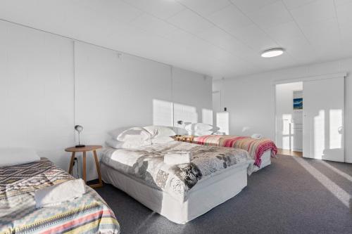 two beds in a room with white walls at Pukehina Estuary Sunset Views Holiday Home in Pukehina
