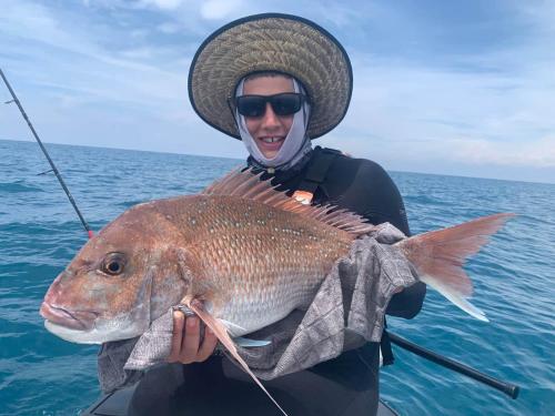 a man in a hat holding a large fish at Pukehina Estuary Sunset Views Holiday Home in Pukehina