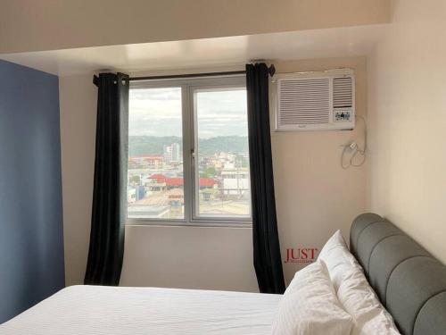 Un dormitorio con una cama y una ventana grande. en Heart of the City CDO Cozy 1Bedroom Wifi Netflix, en Cagayan de Oro