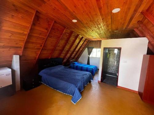 1 dormitorio con 2 camas y techo de madera en Cabaña Chalet La Lomita, en San Gil