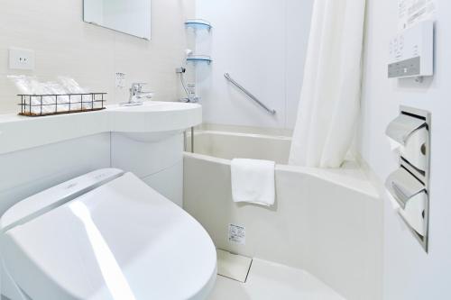 a white bathroom with a toilet and a sink at ICI HOTEL Tokyo Hatchobori in Tokyo