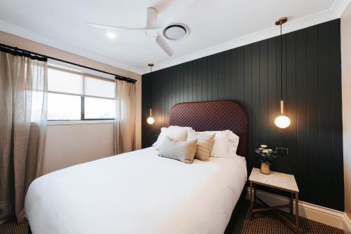 a bedroom with a white bed and a black wall at McKenna Terraces in Mudgee