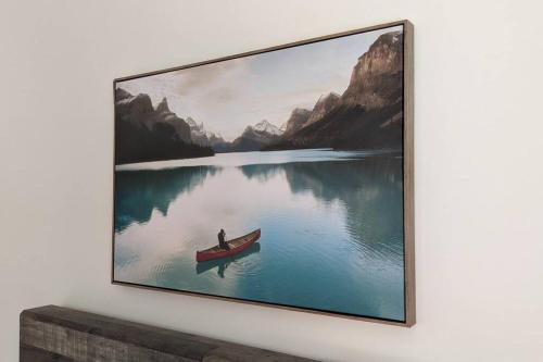 a painting of a man in a boat on a lake at Chalet L'Écureuil (waterfront, modern, spa, BBQ) in Chertsey