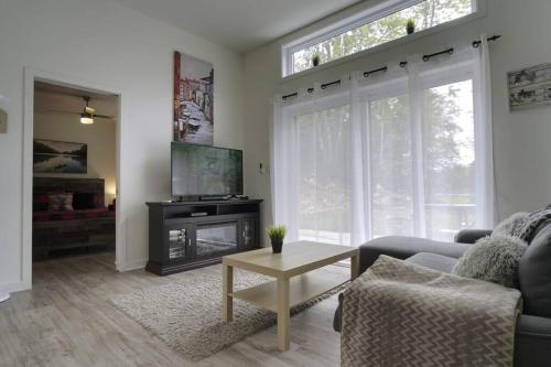 a living room with a couch and a tv and a table at Chalet L'Écureuil (waterfront, modern, spa, BBQ) in Chertsey