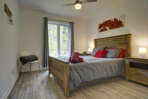 a bedroom with a large bed with red pillows on it at Chalet L'Écureuil (waterfront, modern, spa, BBQ) in Chertsey