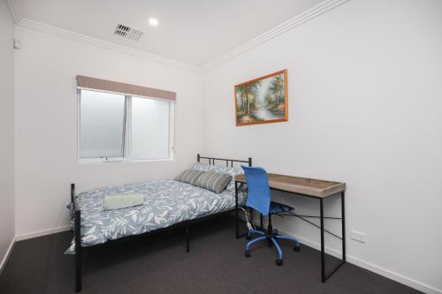 a bedroom with a bed and a desk and a window at Modern Share house, private bedroom with double size bed, 7min to beach in Oaklands