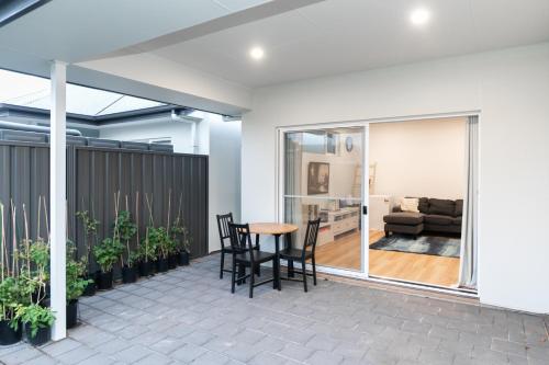 a patio with a table and chairs and a couch at Modern Share house, private bedroom with double size bed, 7min to beach in Oaklands