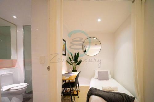 1 dormitorio con cama, mesa y espejo en Zen Seaside 1BR Waterfront Apt, en Darwin