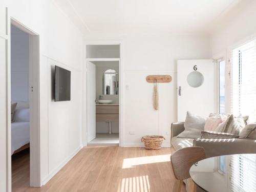 a white living room with a couch and a television at No 6 ShoalHaven in Shoal Bay
