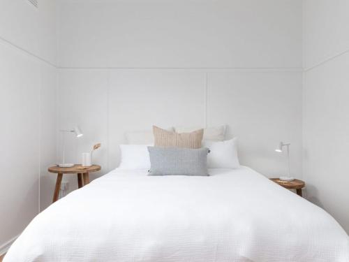 un letto bianco con lenzuola e cuscini bianchi di No 6 ShoalHaven a Shoal Bay