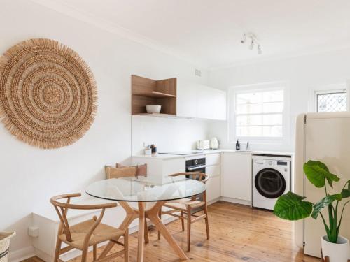 a white kitchen with a glass table and chairs at No 3 ShoalHaven - 1 bed option in Shoal Bay