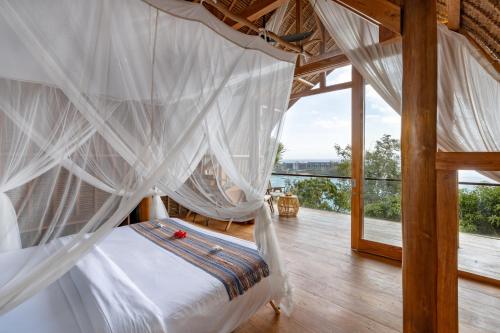 Morin Resort في نوسا ليمبونغان: غرفة نوم مع سرير مع ناموسيات بيضاء