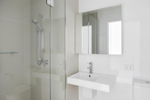 La salle de bains blanche est pourvue d'un lavabo et d'une douche. dans l'établissement Surf Mist, à Newcastle