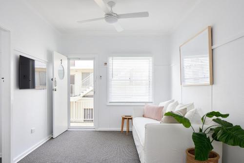 a white living room with a white couch and a plant at No 7 ShoalHaven in Shoal Bay