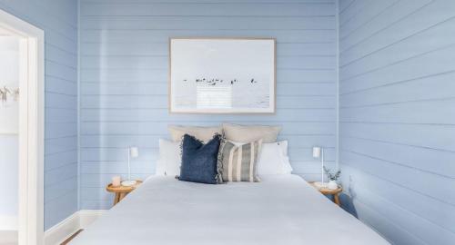 a bedroom with blue walls and a white bed at Pattys Cottage - Pet friendly home in Merewether in Merewether