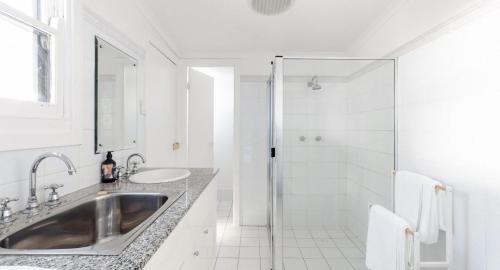 a white bathroom with a sink and a shower at Pattys Cottage - Pet friendly home in Merewether in Merewether