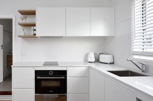 a kitchen with white cabinets and a black oven at No 7 ShoalHaven in Shoal Bay
