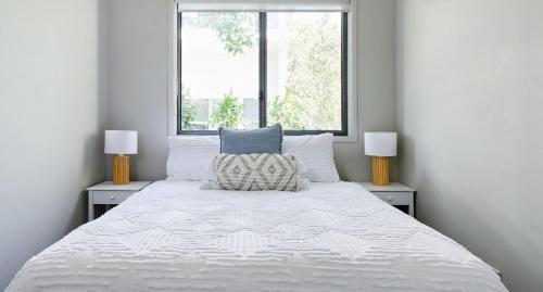 a bedroom with a large white bed with two windows at The Drift in Nelson Bay
