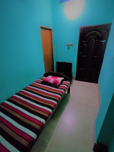 Ce lit se trouve dans un dortoir doté d'un mur bleu. dans l'établissement Ayush Villa, à Sirājganj
