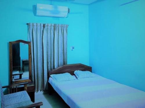 ein blaues Zimmer mit einem Bett und einem Spiegel in der Unterkunft Ayush Villa in Sirājganj