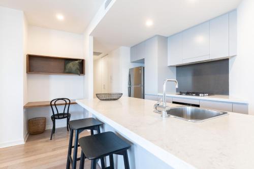 a kitchen with a sink and a counter with stools at The Edge in Newcastle