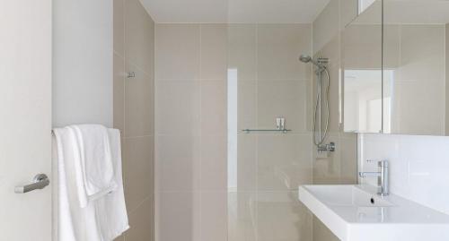 a white bathroom with a sink and a shower at The Grande in Newcastle