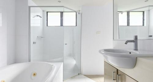 a white bathroom with a sink and a shower at The Shores in Nelson Bay
