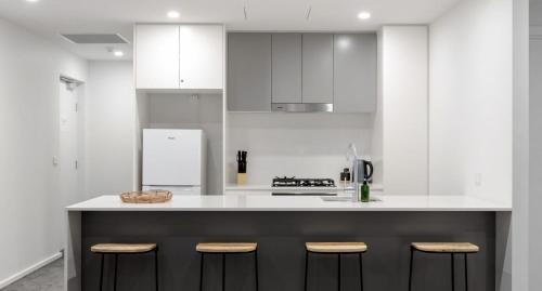 a kitchen with white cabinets and a counter with stools at The Muse - 1 bed option in Newcastle