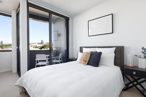 a bedroom with a large white bed and a balcony at The Loft in Newcastle