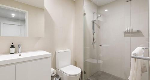 a white bathroom with a toilet and a shower at The Muse in Newcastle