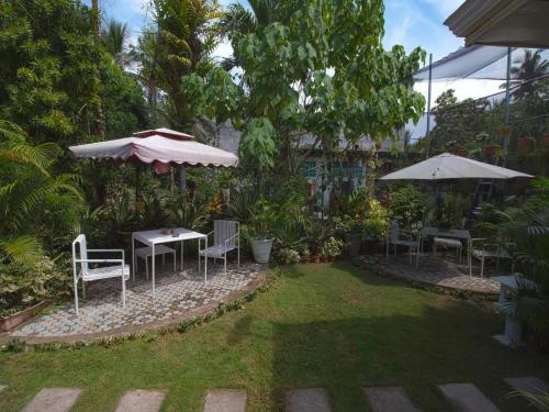 YOO Darius' Residences في موالبوال: حديقة فيها طاولات وكراسي ومظلات