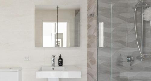 een witte badkamer met een wastafel en een douche bij The Outlook - 2 bed option in Newcastle
