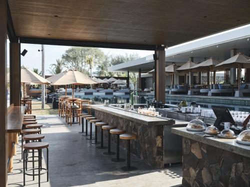 a restaurant with bar stools and tables and umbrellas at BASK Gili Meno in Gili Meno