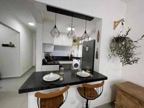 a kitchen with a counter with two chairs and a table at Apartamento quarteirão da praia (Boqueirão) in Santos