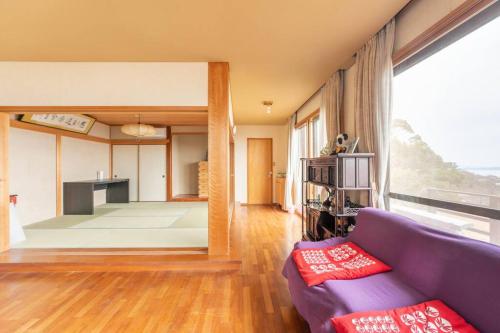 Ajiro的住宿－熱海網代 太平洋一望和式貸切一軒家 庭でバーベキュー，客厅配有紫色沙发和大窗户