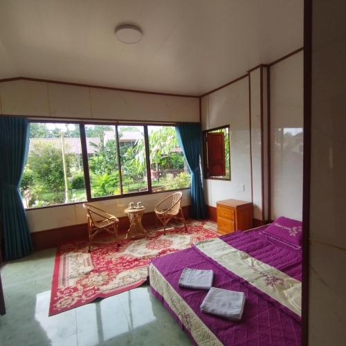 a bedroom with a purple bed and a large window at Brown House Resort in Can Tho
