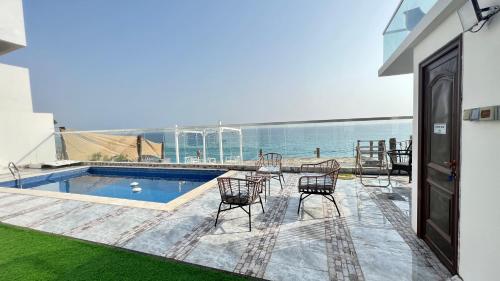 a patio with a pool and chairs and the ocean at Wadi Shab Beach Villa in Sur