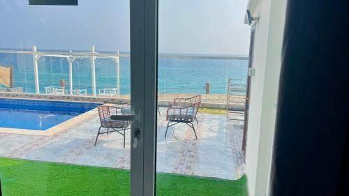a sliding glass door with a view of the ocean at Wadi Shab Beach Villa in Sur