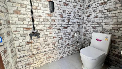 a bathroom with a white toilet in a brick wall at Wadi Shab Beach Villa in Sur