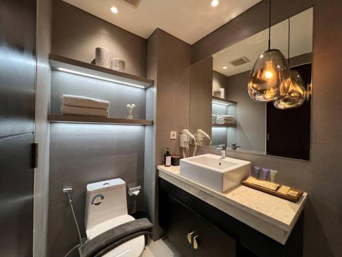 a bathroom with a white toilet and a sink at Monochromic Studio Apartment by Kinasih Suites in Kejayan