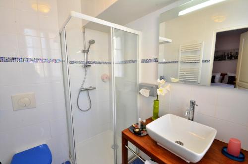 a white bathroom with a shower and a sink at Hôtel du Fort in Meulan