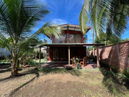 a house with a balcony and a palm tree at Tortuguero Hill Rooms in Tortuguero